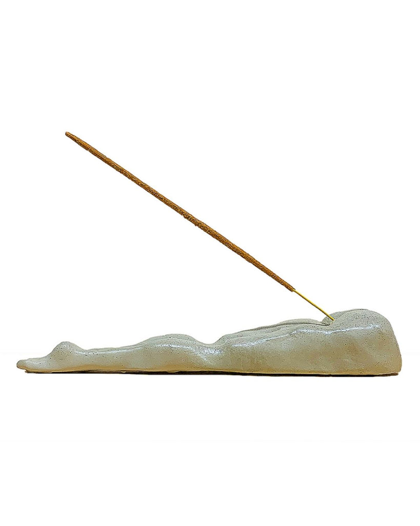 Burner is shown with an incense in it against a white backdrop. 